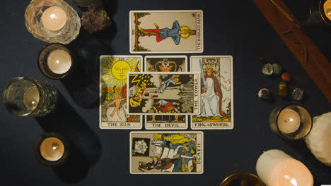 Overhead-Shot-Of-Person-Giving-Tarot-Card-Reading-Laying-Down-Cards-On-Table-With-Candles-And-Crystals-5